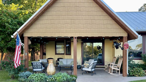 A covered outdoor seating area with a patio table, chairs, and a large vase.