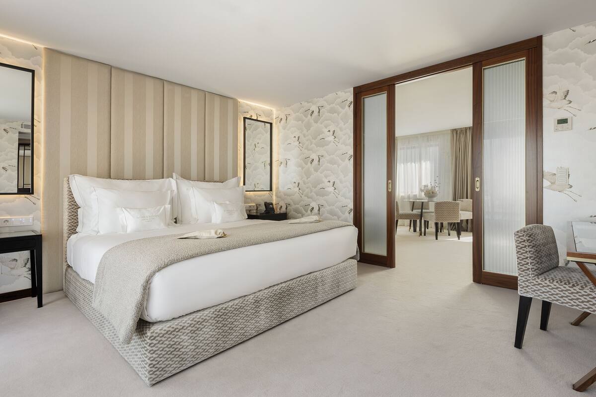 A spacious bedroom with a large bed, a bedside table, and a chair.