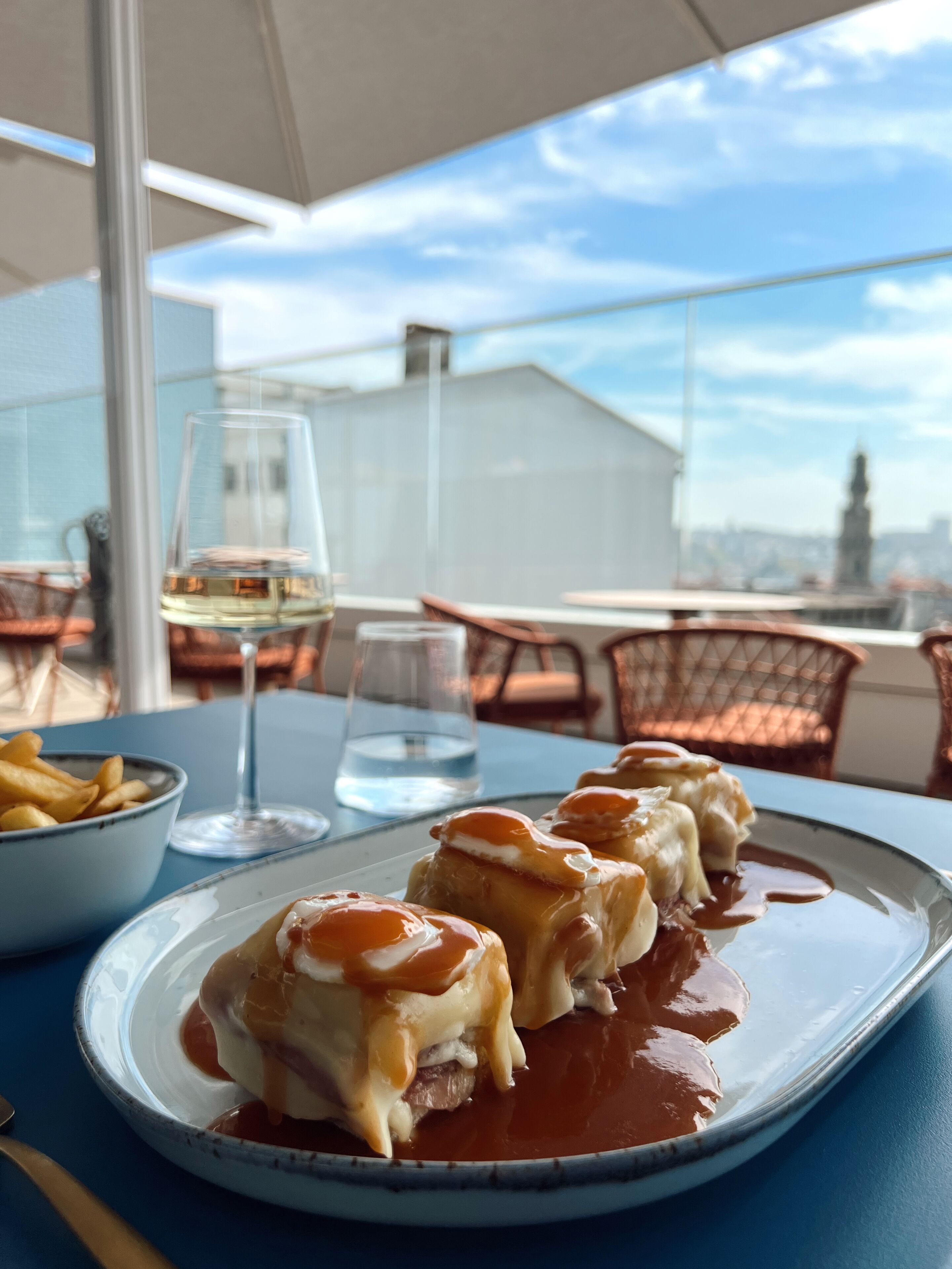 Et spisebord med mad, et glas hvidvin og en skål pommes frites.