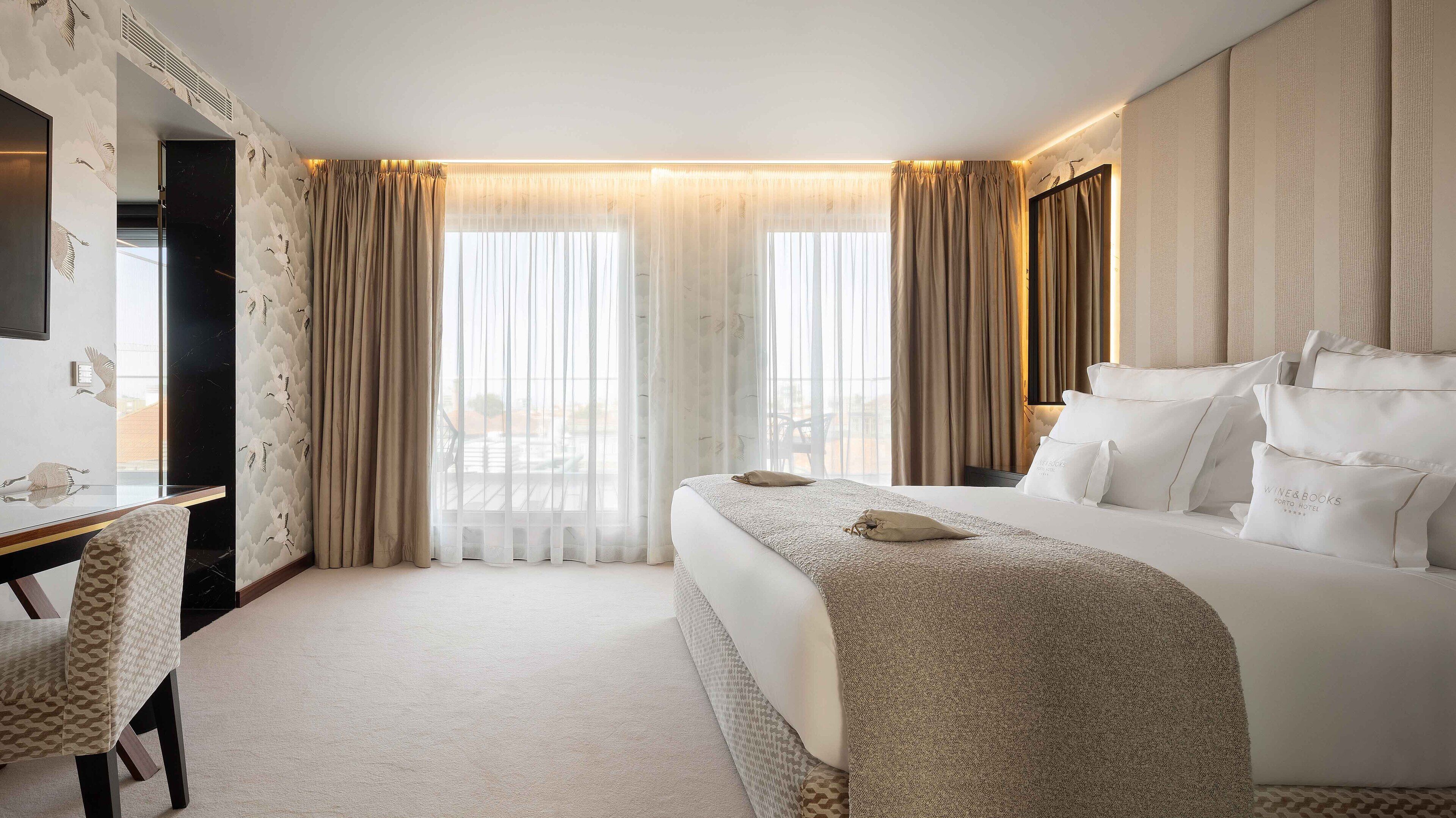 A hotel room with a large bed, a desk, and a chair.