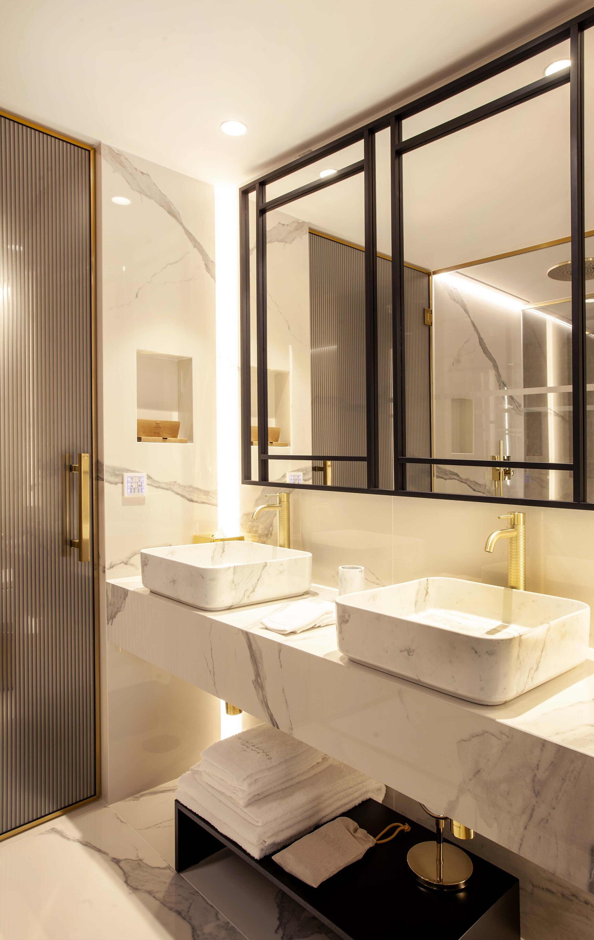 A modern bathroom with two sinks, a large mirror, and a walk-in shower.