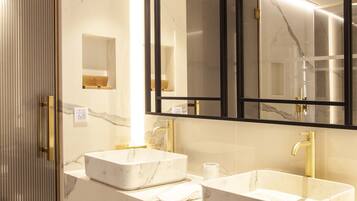 A modern bathroom with two sinks, a large mirror, and a walk-in shower.