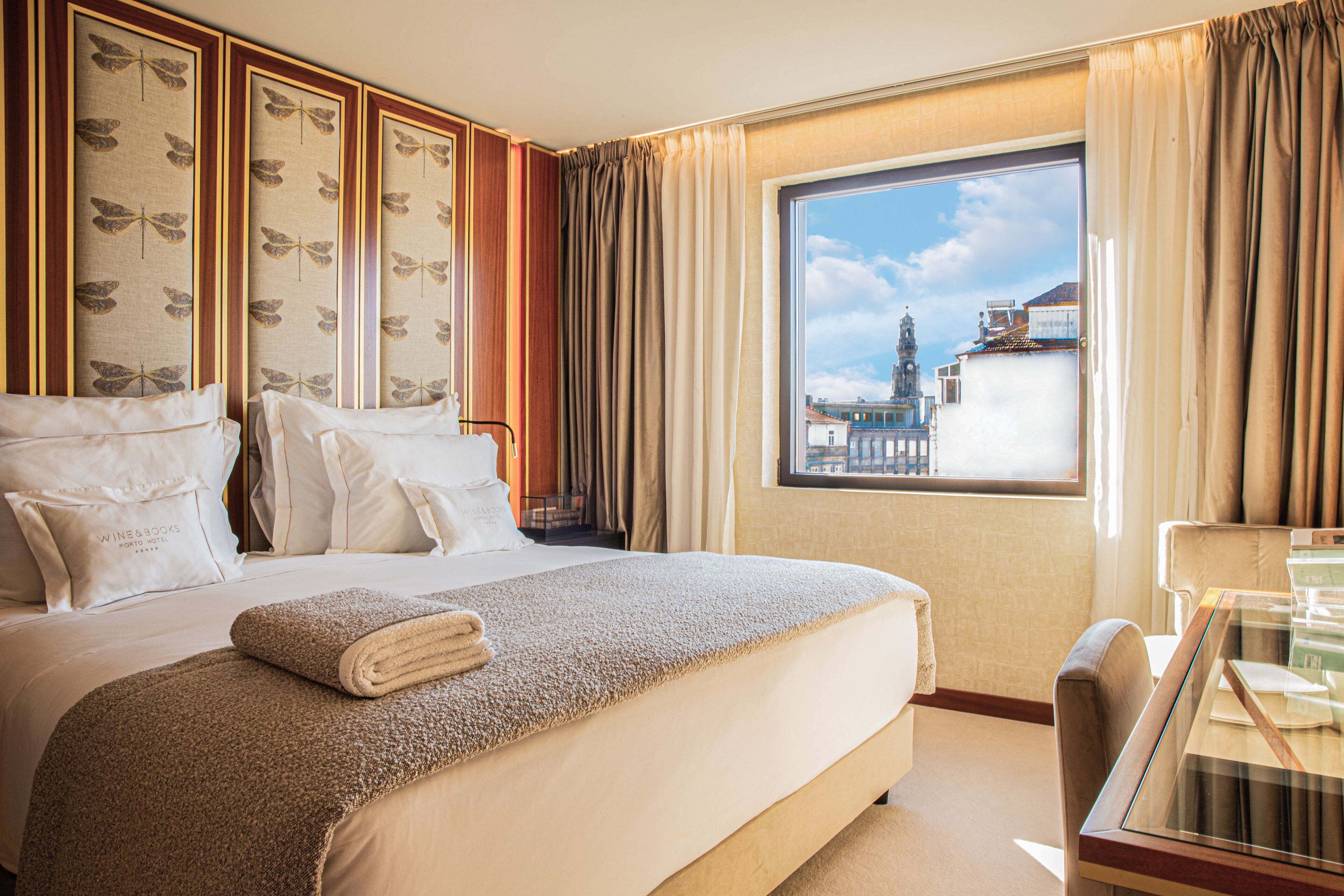 A hotel room with a large bed, a desk, and a window with a view of a building.