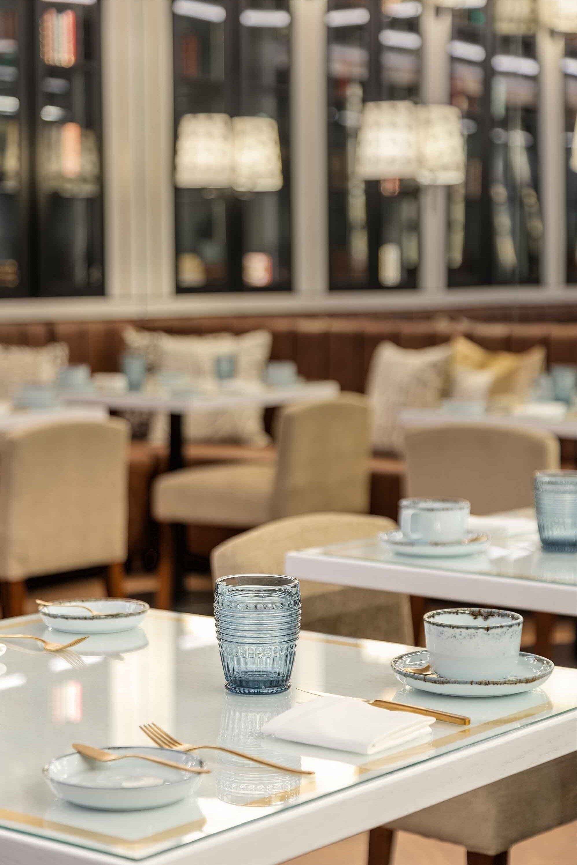 A restaurant with tables set for dining, featuring glassware and plates.
