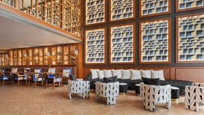 A spacious reading room with a high ceiling, wooden bookshelves, and a large seating area with patterned ottomans and a black sofa. - Wine & Books Porto Hotel - Small Luxury Hotels of the World (Porto)