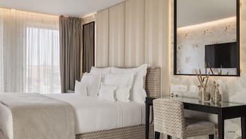 Une chambre d’hôtel avec un grand lit, un bureau et une chaise. Il y a un grand miroir au mur et une fenêtre avec des rideaux.
