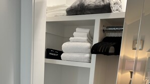 Un armario ordenado con estantes que contienen toallas dobladas, un neceser y cajas de almacenamiento.