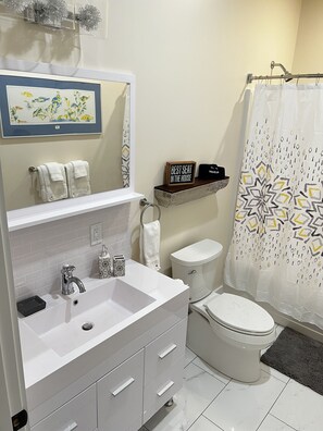 Une salle de bain moderne avec un meuble-lavabo blanc, des toilettes et un rideau de douche.