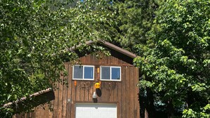 Eine Holztankstelle mit einer weißen Tür, zwei Fenstern und einer kleinen Veranda.