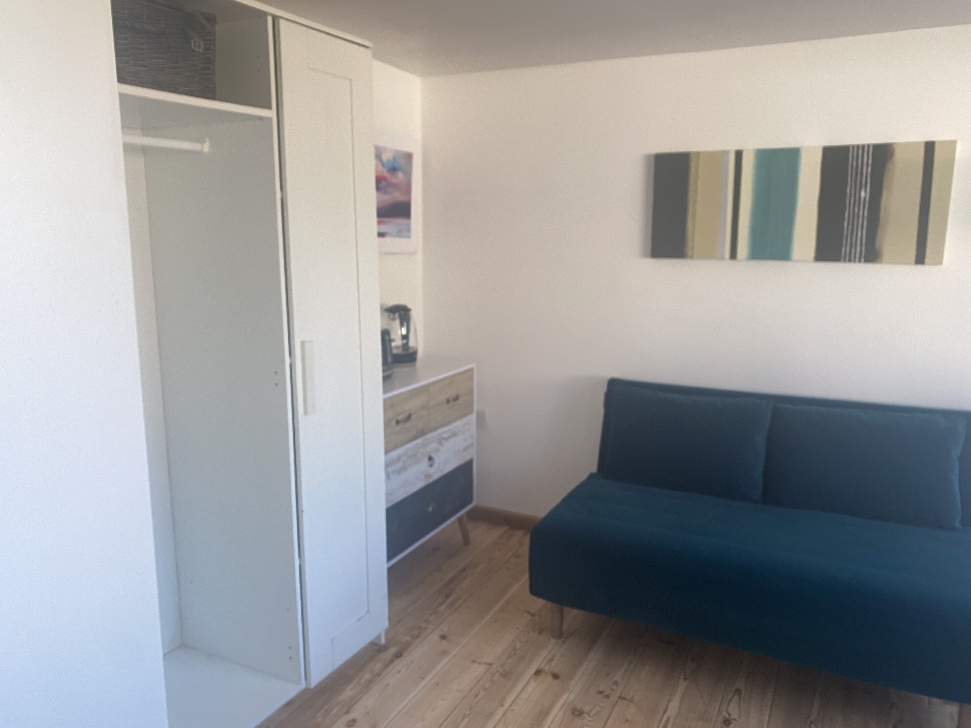 A room with a wardrobe, a dresser, and a sofa.