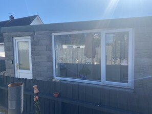 Et hus med en stenvæg, et vindue med hvide rammer og en dør med glasrude.