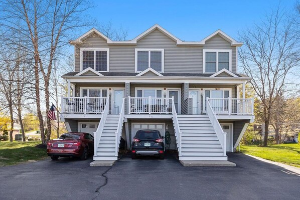 Une maison à deux étages avec un porche à l’avant, deux garages et une allée.