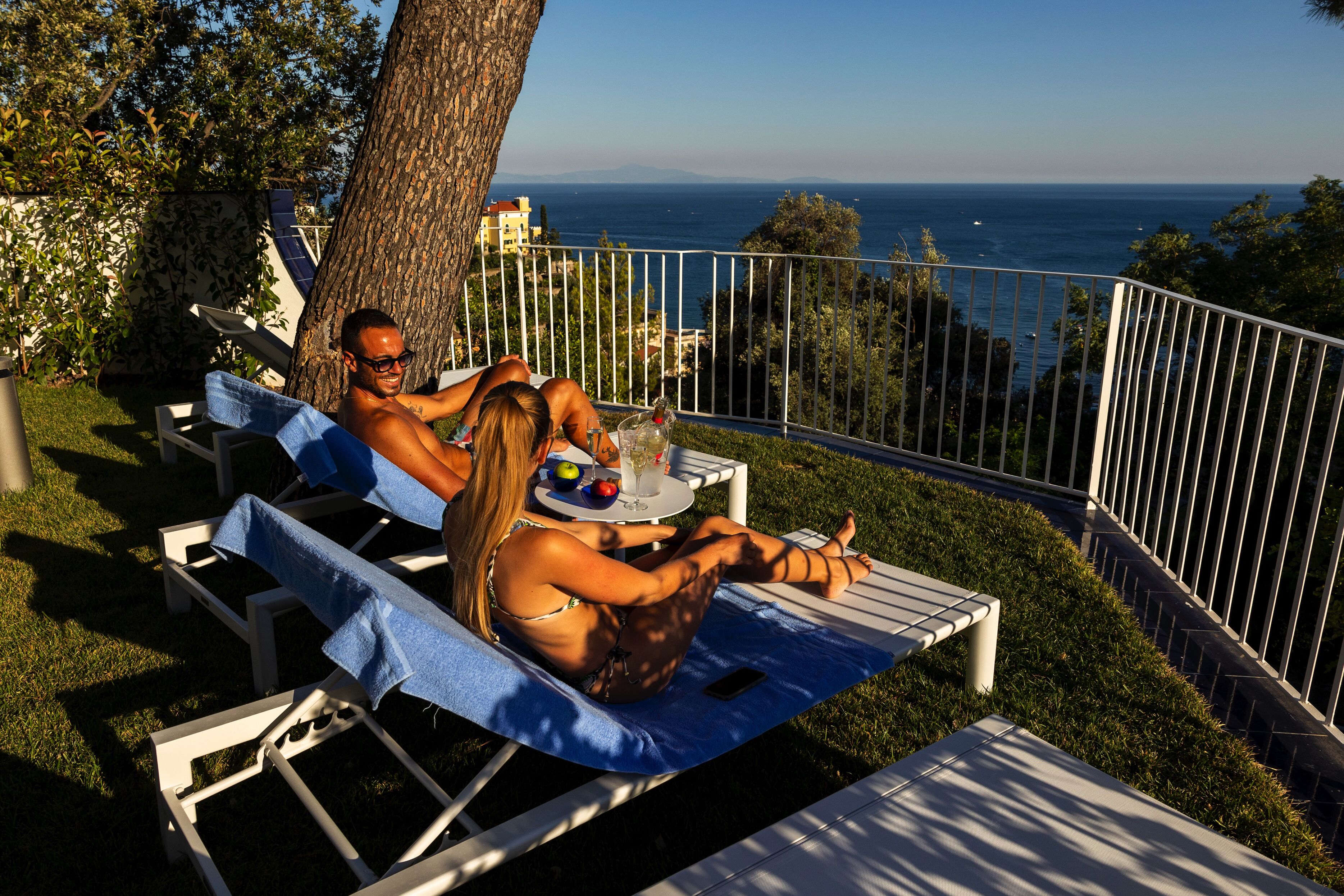 A couple relaxing on a sun lounger with a view of the sea.