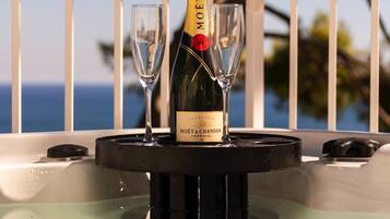 A bottle of Moรซt & Chandon champagne on a table with two glasses, set against a balcony with a view of the sea.