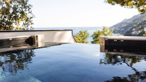 Vista despejada de una piscina infinita con el paisaje de montañas al fondo.