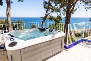 Ein Whirlpool mit freiem Blick auf das Meer und einem weißen Zaun.