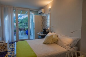 Ein Hotelzimmer mit Bett, Schreibtisch, Stuhl und Blick auf einen Balkon mit Tisch und Stühlen.