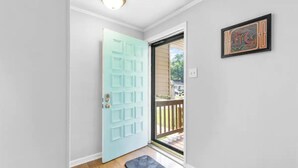 Uma porta com painel azul claro, um tapete pequeno no chão e um quadro pendurado na parede.