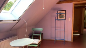 A room with a sloped ceiling, a table with chairs, a radiator, and a door leading to another room. - Privelacker Paradiesgarten (Amt Neuhaus)