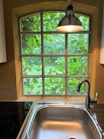 Una cocina con ventana, un lavamanos y una lámpara colgante.