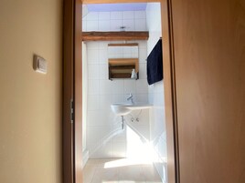 Un baño con lavamanos blanco, un espejo y una viga de madera sobre el lavamanos.