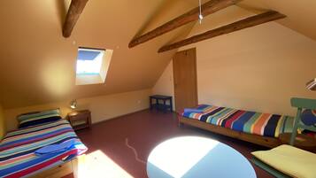 A small, cozy room with two beds, a round table, and a window.