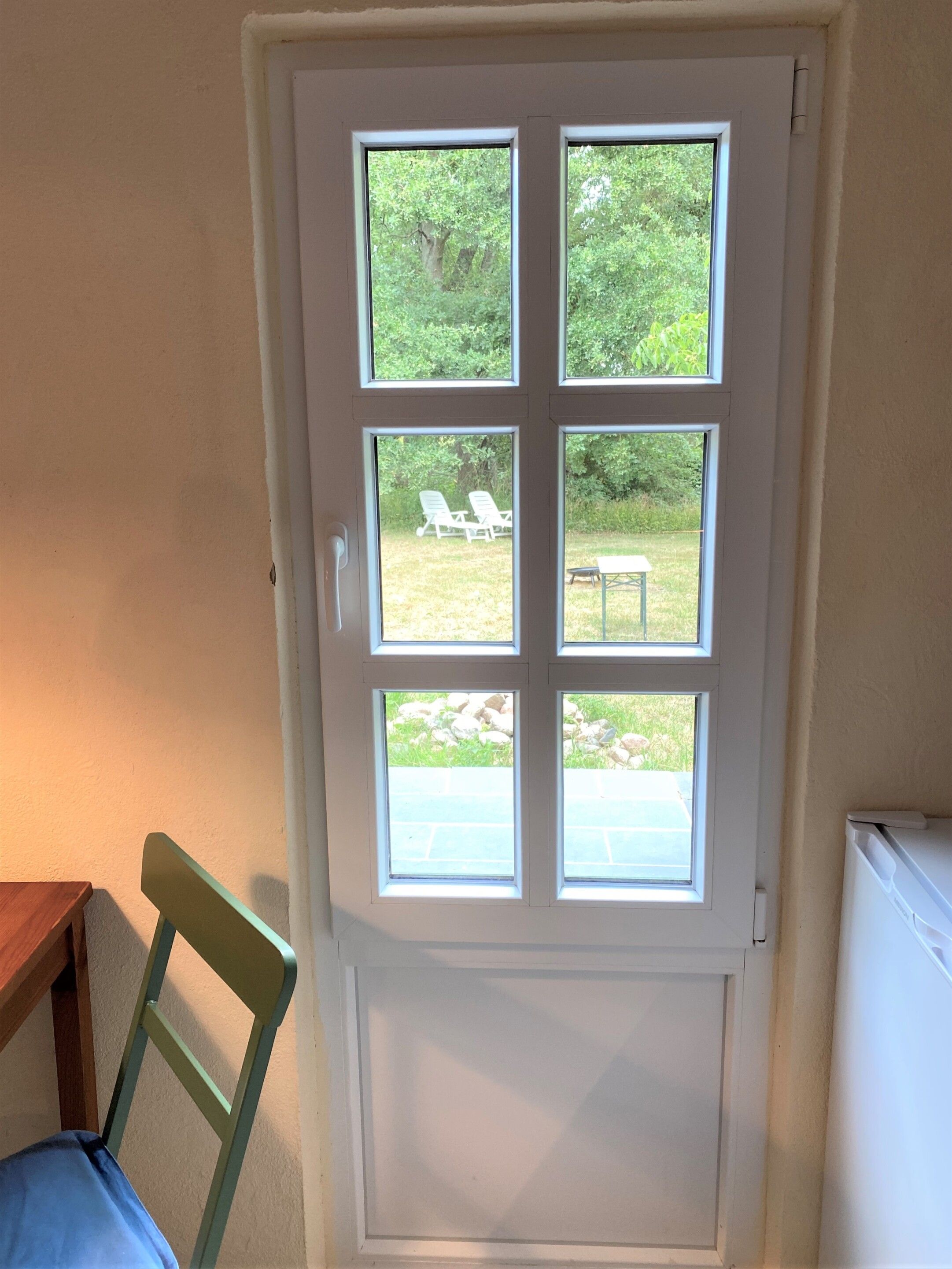 A door with a view of an outdoor area including a lawn, chairs, and a table.