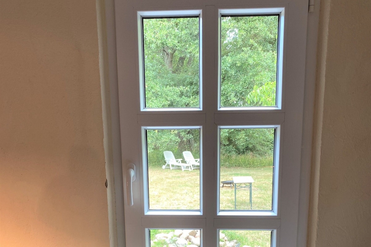A door with a view of an outdoor area including a lawn, chairs, and a table.