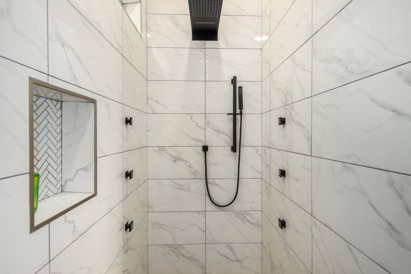 A shower with a handheld showerhead and a wall-mounted control panel.