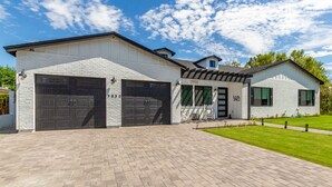 Uma casa moderna de dois andares com garagem, varanda coberta e gramado bem cuidado.