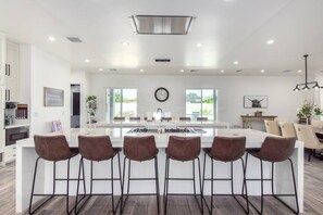 Une cuisine moderne dotée d’un îlot central, de tabourets de bar et d’un coin repas avec des chaises.