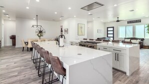 Cozinha espaçosa com uma ilha grande, eletrodomésticos modernos e área de jantar com banquetas.