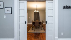 A dining area with a table and chairs, a chandelier, and a rug on the floor. - The Colonels Apartment is a freshly renovated 3bedroom 1bath downtown Richmond apartment (Richmond)