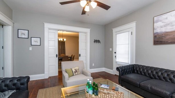 A living room with a glass coffee table, two sofas, a ceiling fan, and a dining area in the background. - The Colonels Apartment is a freshly renovated 3bedroom 1bath downtown Richmond apartment (Richmond)