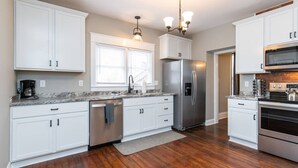 A modern kitchen with white cabinets, stainless steel appliances, and a wooden floor. - The Colonels Apartment is a freshly renovated 3bedroom 1bath downtown Richmond apartment (Richmond)