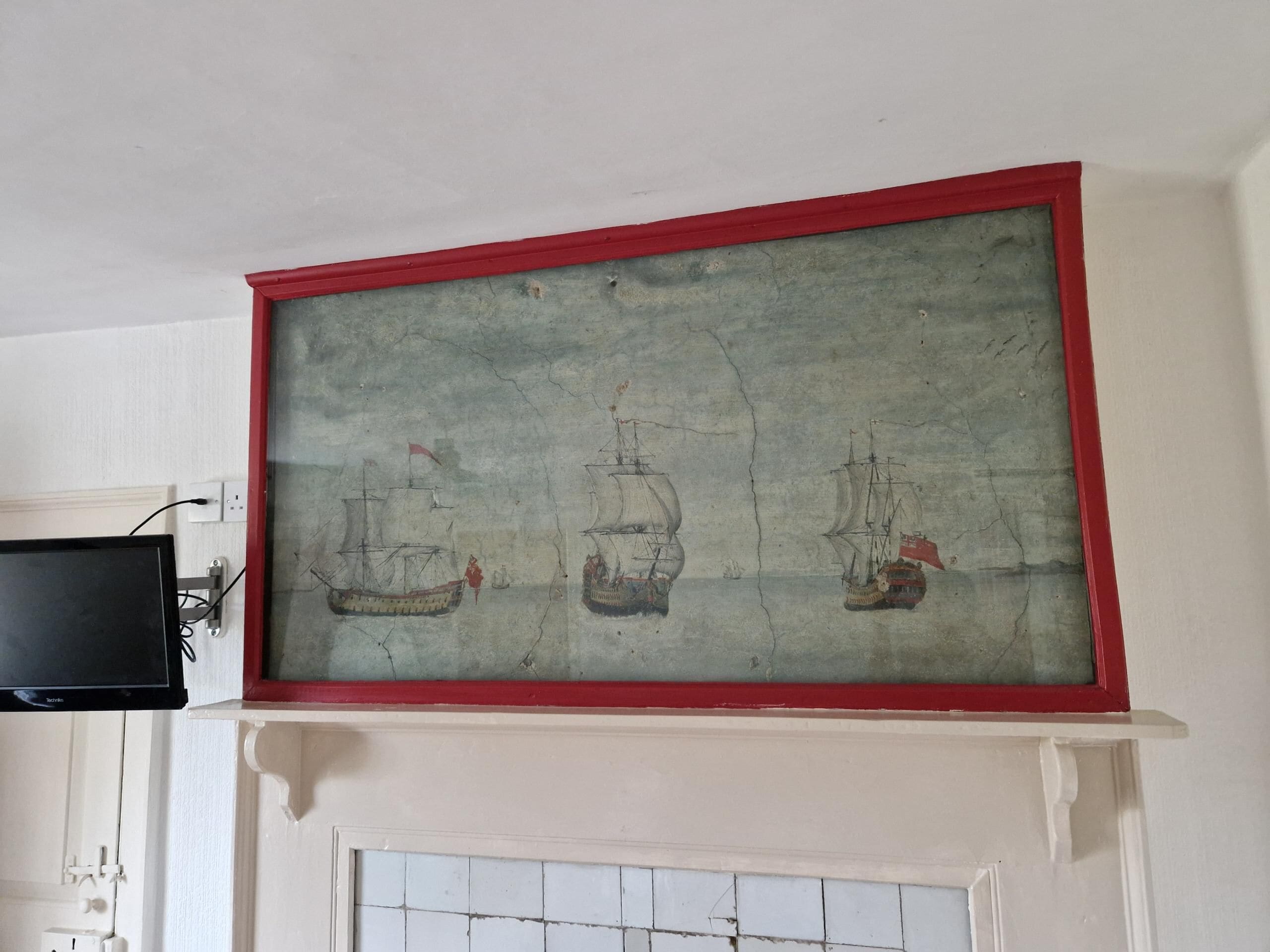 A framed artwork of three ships on a wall above a fireplace.