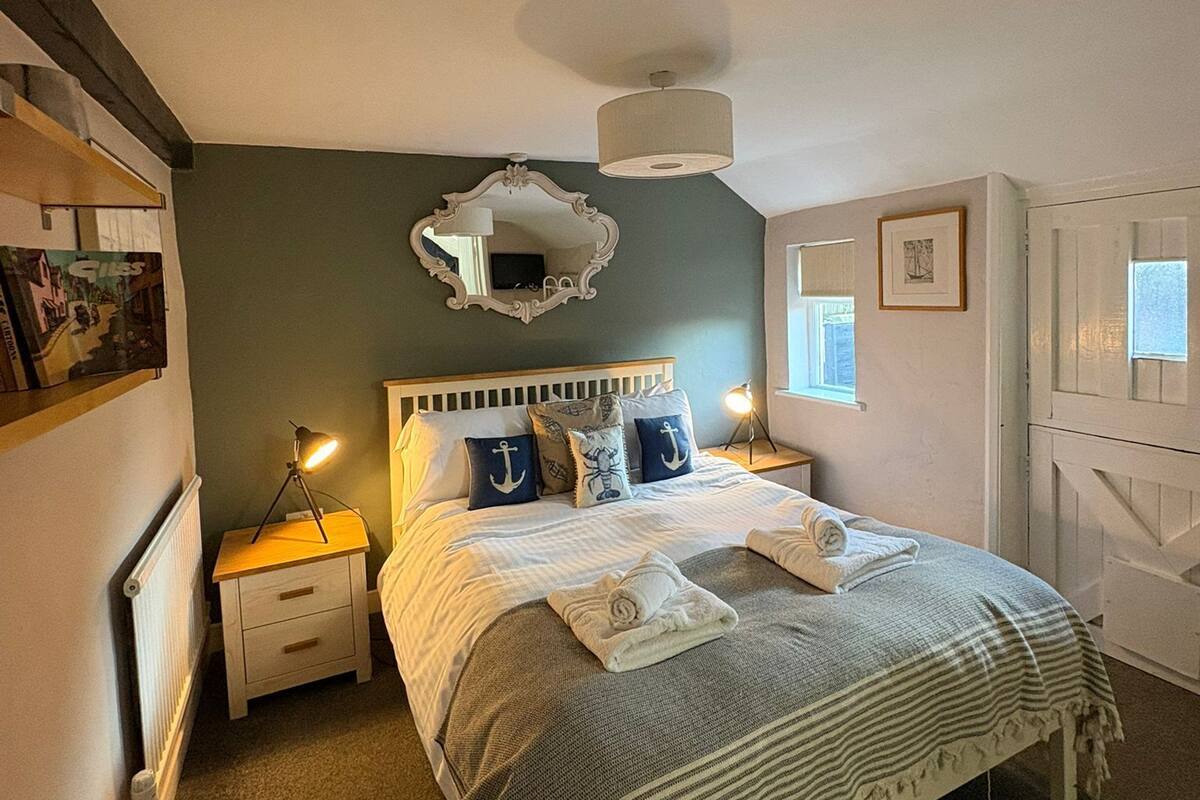 A bedroom with a bed, bedside lamps, a mirror, and a radiator.