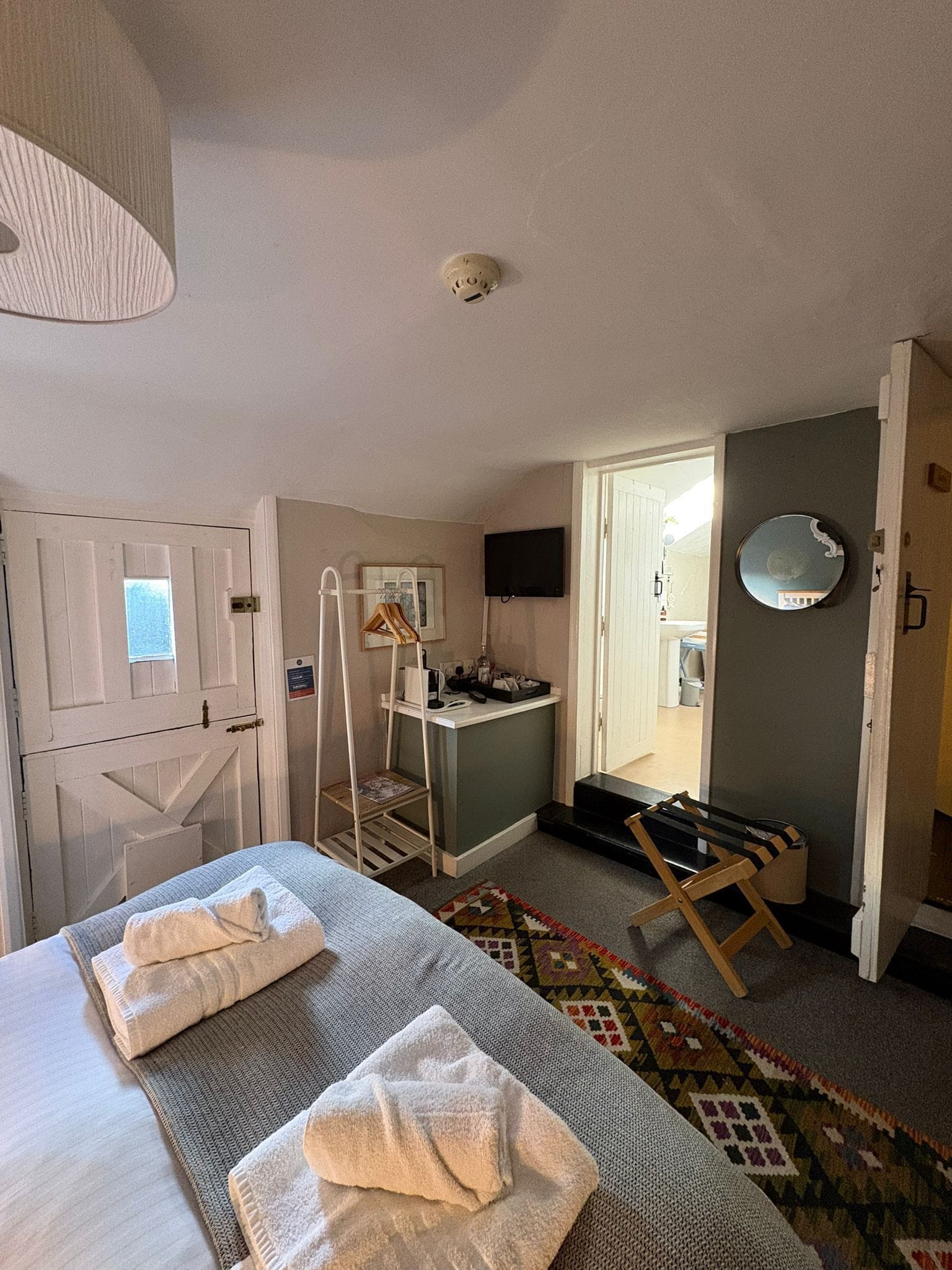 A hotel room with a bed, a desk, a chair, a television, and a door leading to a bathroom.