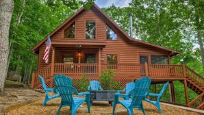 Une cabane en bois avec un porche, deux fauteuils Adirondack et un drapeau américain.
