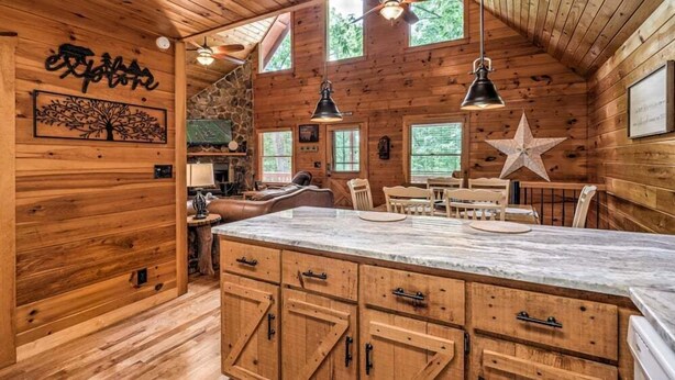 L’intérieur d’un chalet en bois présente un grand comptoir central, des murs en pierre et une décoration à motifs d’étoiles.
