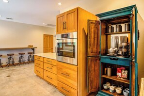 A kitchen with wooden cabinets, a built-in oven, and a coffee station.