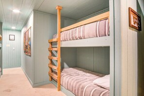 A bunk bed with a wooden ladder, a framed picture on the wall, and a light-colored floor.
