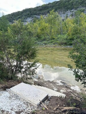 Un paisaje natural con un cuerpo de agua, árboles y terreno rocoso.