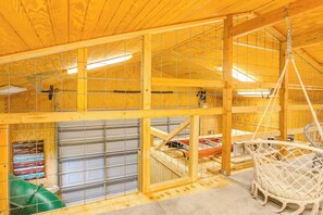 A multi-level wooden structure with a hanging chair, a garage with a car, and a green container. - Roadrunner | Riverfront 3BR with Views & Fire Pit (Leakey)