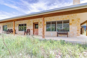 A stone building with a covered porch, outdoor seating, and a view of the surrounding landscape.