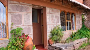 Un edificio de piedra con fachada rústica, una puerta de madera y una ventana con cortina a rayas.