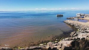 Escena costera con aguas tranquilas, una costa rocosa y barcos.