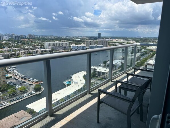 Enjoy breathtaking views of the marina and urban landscape from this balcony with a seating area.
