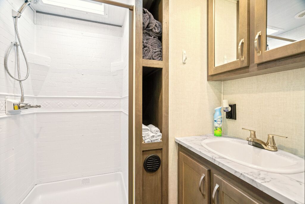 Un baño con una bañera blanca, ducha, armarios de madera y un lavabo con encimera de mármol.