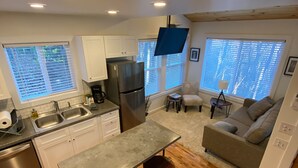 A compact kitchen with a refrigerator, double sink, and wooden flooring. - Charming Cottage Near Downtown, Parkway, and Biltmore (Asheville)
